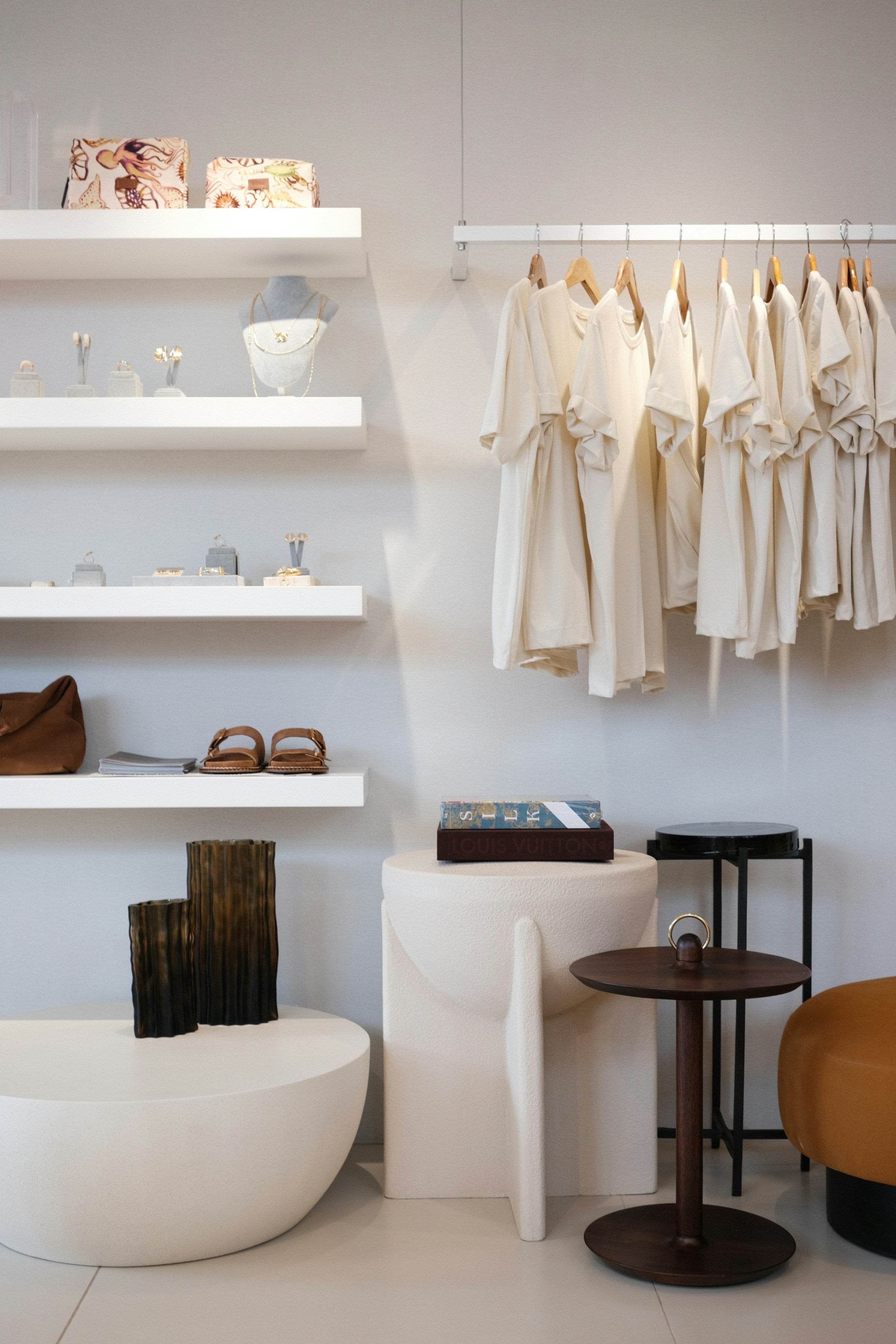 Interior minimalista de boutique con prendas en tonos marfil